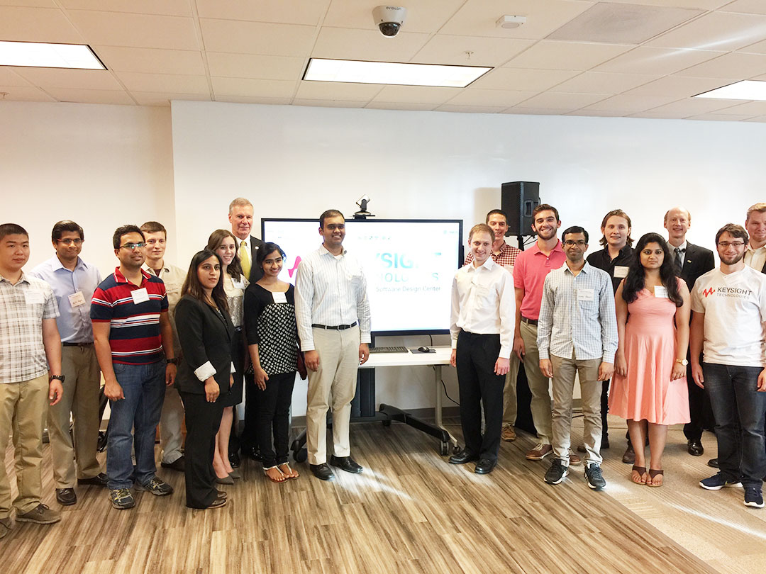 A large diverse group of young people stands with the Georgia Tech president in front of a screen that reads Keysight Technologies